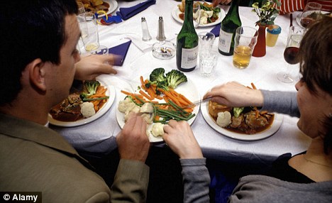 A couple share vegetables during a roast dinner meal